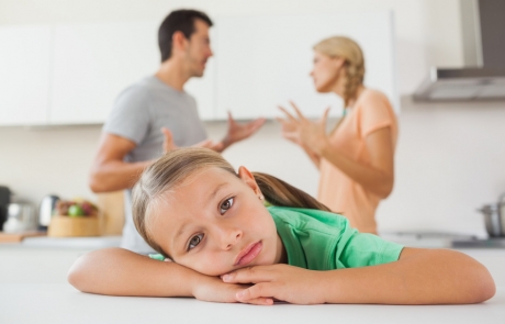 Angry couple arguing behind a sad girl at home